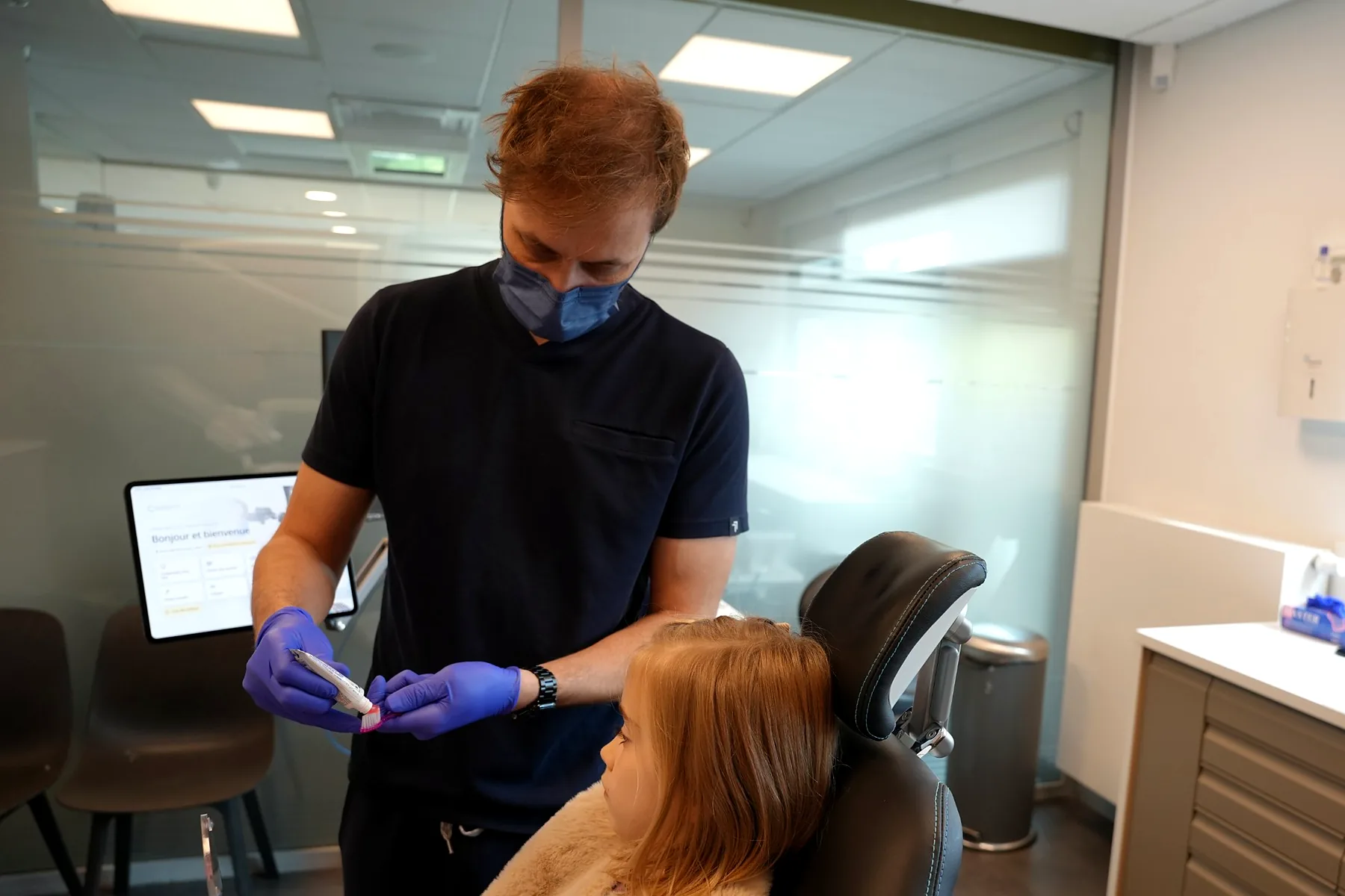 Le dentiste dépose une petite quantité de dentifrice sur la brosse d’une enfant